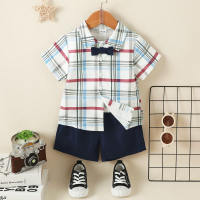 طقم للطفل الصغير مكون من قطعتين، يتضمن قميصًا بأكمام قصيرة بتصميم مقسم بنقوش مربعات ملونة مع عقدة عنق (بوتاي)، وشورت بلون صلب.  أزرق