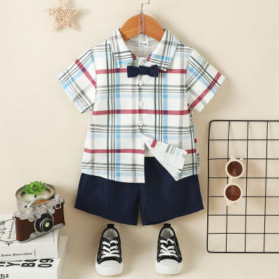 طقم للطفل الصغير مكون من قطعتين، يتضمن قميصًا بأكمام قصيرة بتصميم مقسم بنقوش مربعات ملونة مع عقدة عنق (بوتاي)، وشورت بلون صلب.